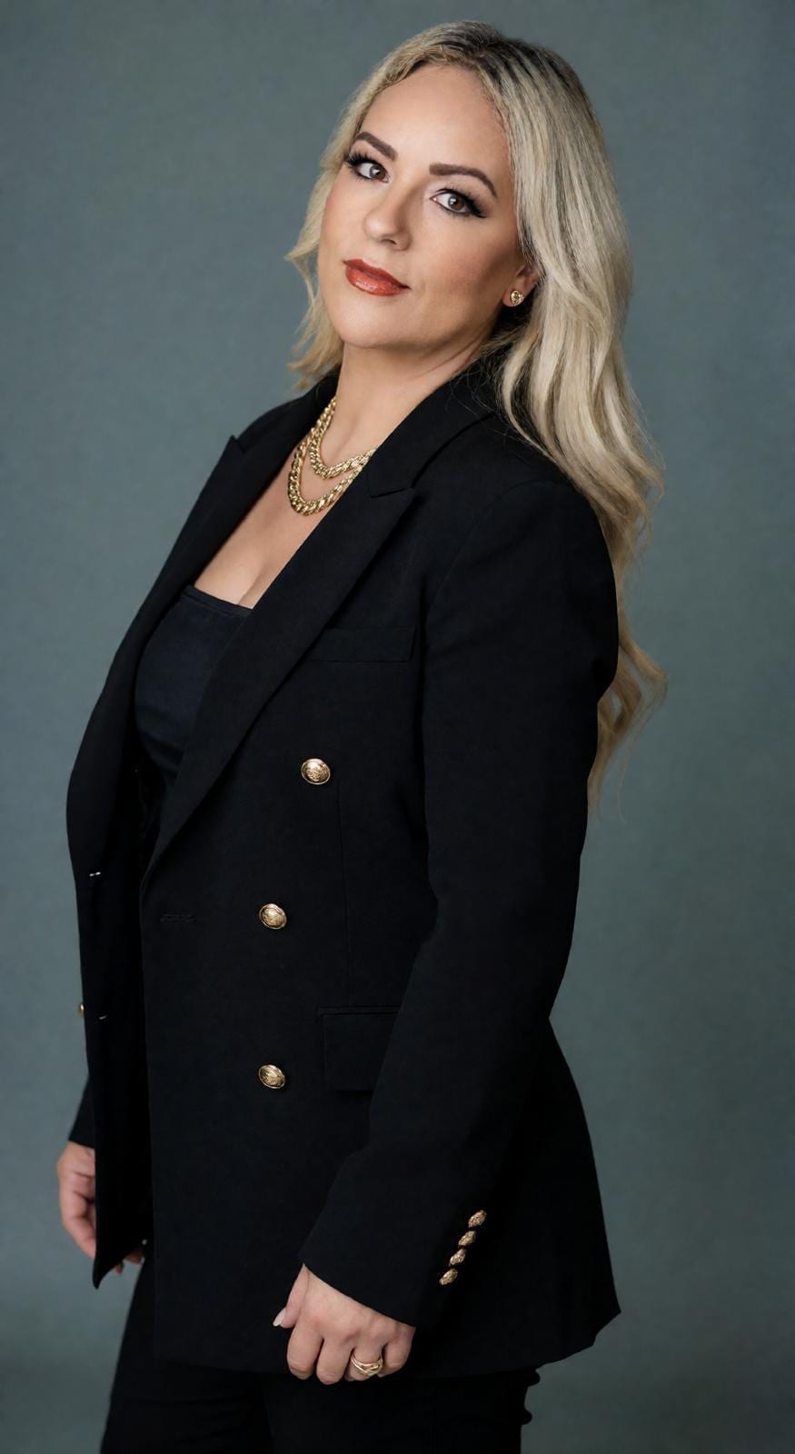 Aldina Sousa wearing a black blazer, hands on her waist, looking at the camera
